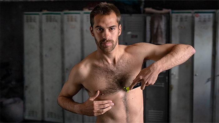 Topless man in locker-room shaves centre of chest using the Philips OneBlade as a beard and body trimmer.